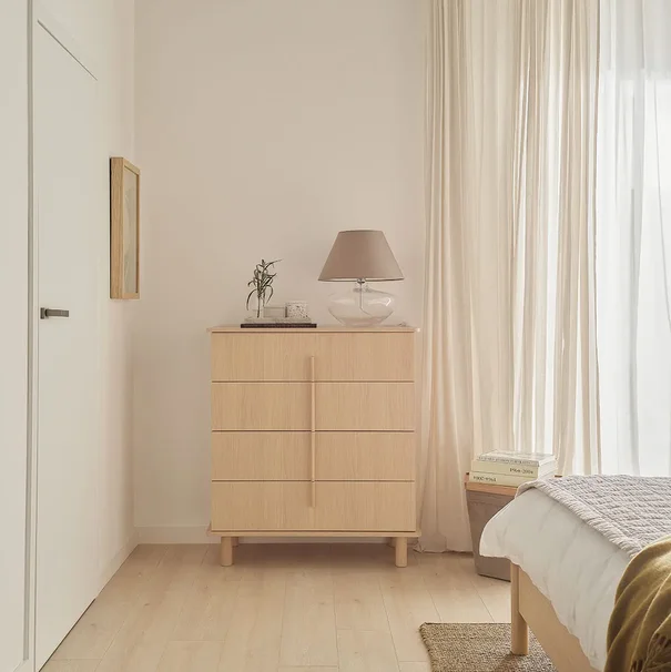 jasna, drewniana komoda ze szklaną lampą i dekoracjami